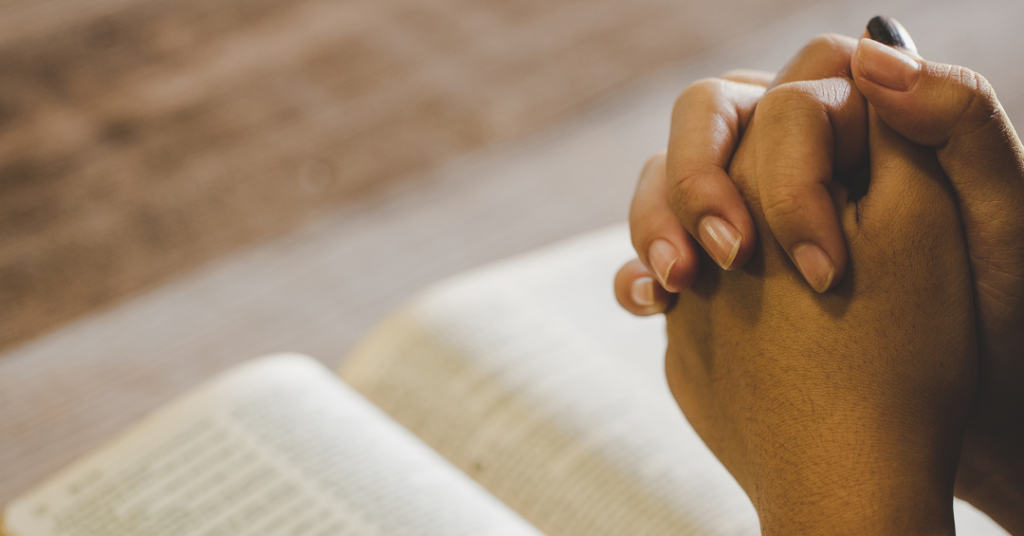 woman's praying hands over an open Bible - claiming the Joshua 1:9 promise